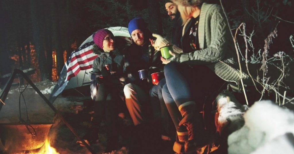 Winter campers gathered around the warmth of a fire, sharing stories and hot beverages.